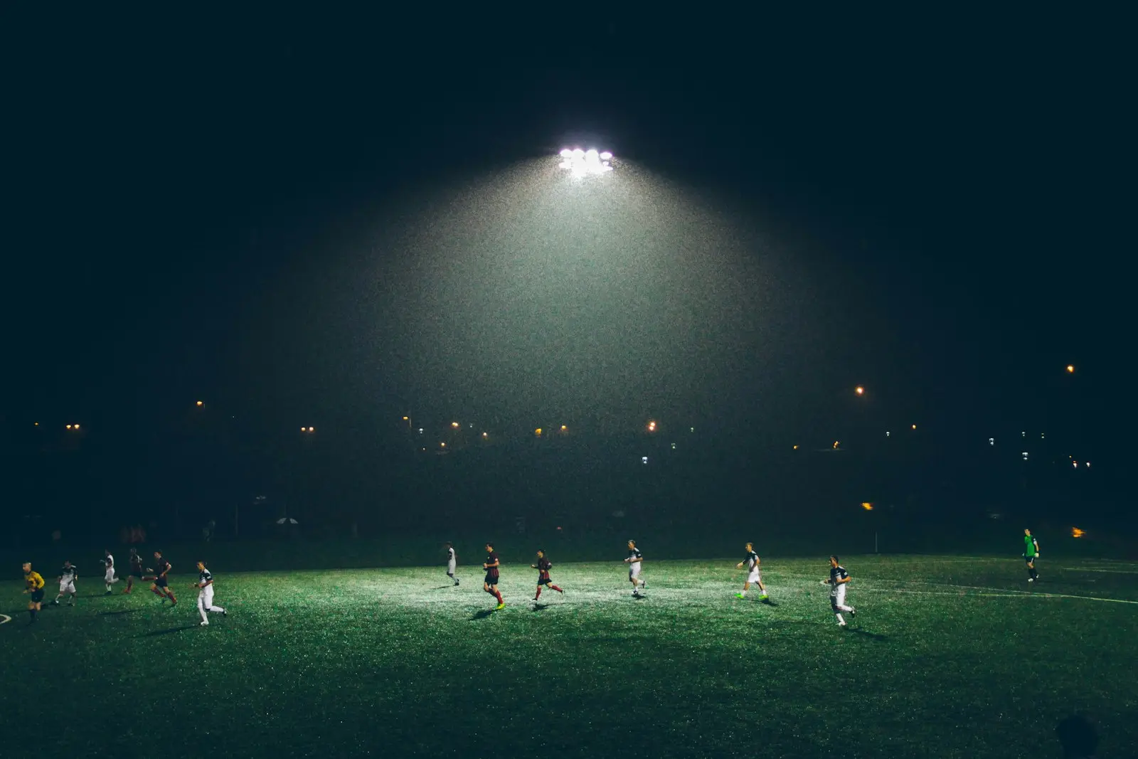 Spelers trainen op het veld onder de lichtmasten